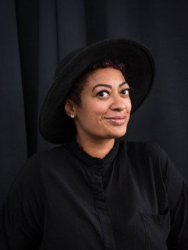 portrait of woman with black clothes and hat in front of black background 
