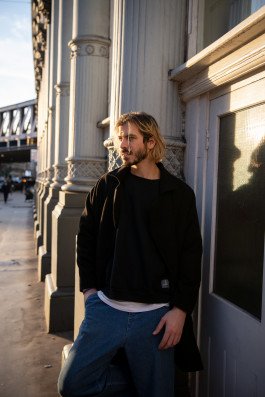 location portrait of young man outdoors standing near building urban environment with sunlight natural light 